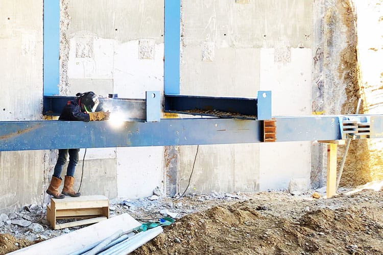 Welder securing large steel brackets to waling beam at Paddington Cube site